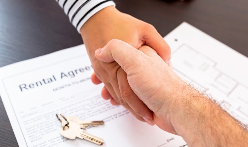 cropped image of property owner and tenant shaking hand after signing a rental agreement