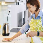 young woman disinfecting a kitchen countertop
