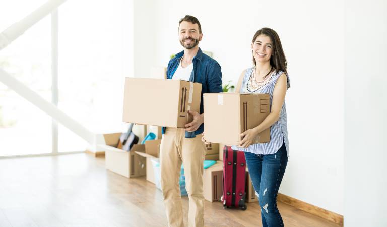 couple holding boxes in hand inside a room