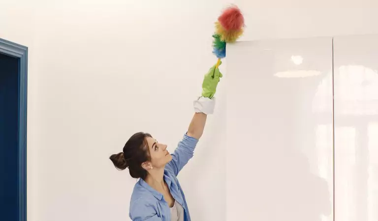 young woman trying to clean walls and ceilings