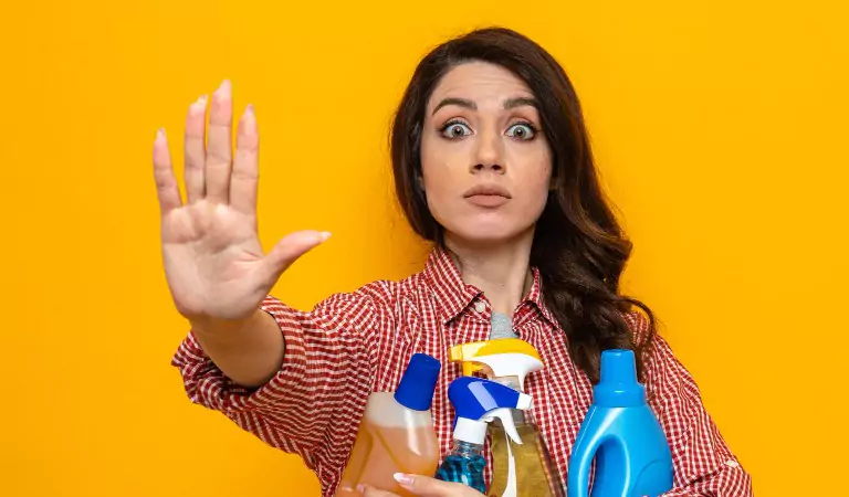 woman with cleaning supplies showing her hand and looking stressed