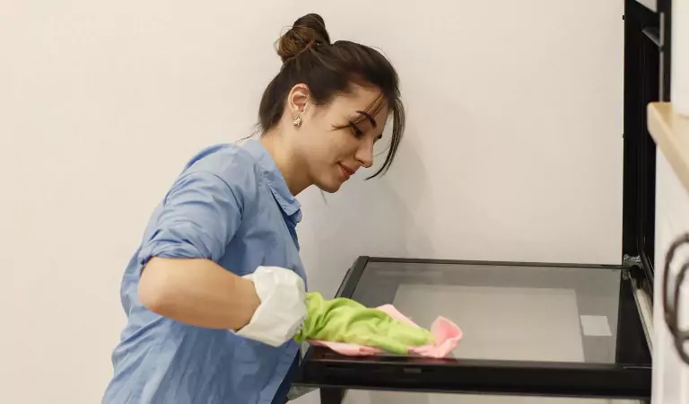 young woman cleaning a kitchen appliance