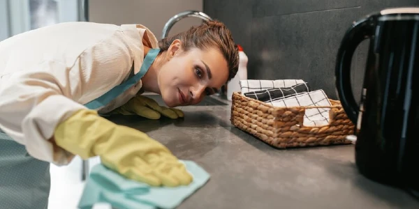 Woman in yellow gloves cleaning a table with a cloth.