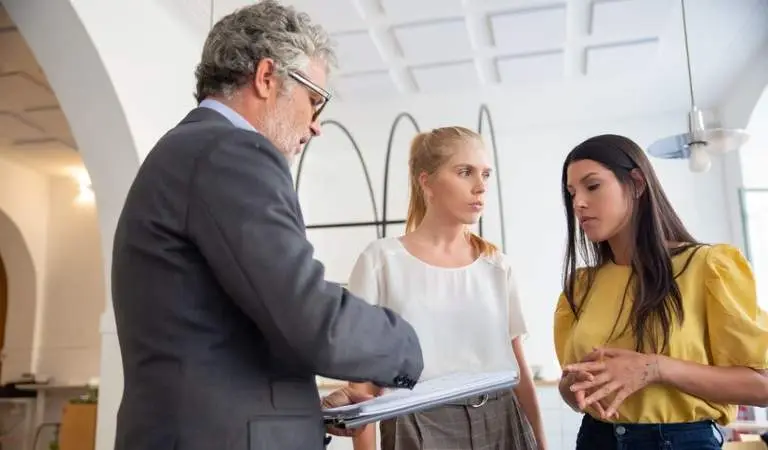 Landlord holding a file in his hand and talking to two ladies.