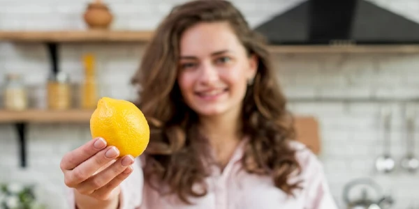 A lady holding a lemon in her hand inside her kitchen