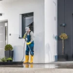 Men cleaning his house surrounding using pressure washing machine