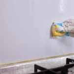 Cleaning the kitchen wall effectively with a sponge and some good detergent for hygiene