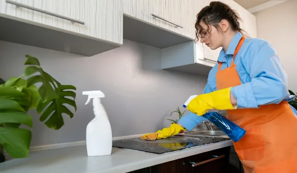 Young woman in an apron cleaning the kitchen ecocleaning using natural and ecofriendly