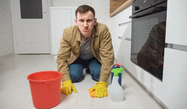 Man cleans floor with detergent and water in kitchen